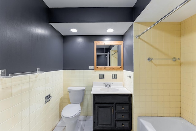 full bathroom with tile walls, tiled shower / bath combo, vanity, toilet, and tile patterned floors