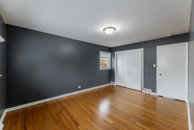 unfurnished bedroom featuring two closets and light hardwood / wood-style flooring