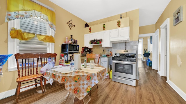 kitchen with white cabinets, decorative backsplash, stainless steel range with gas stovetop, and light hardwood / wood-style flooring