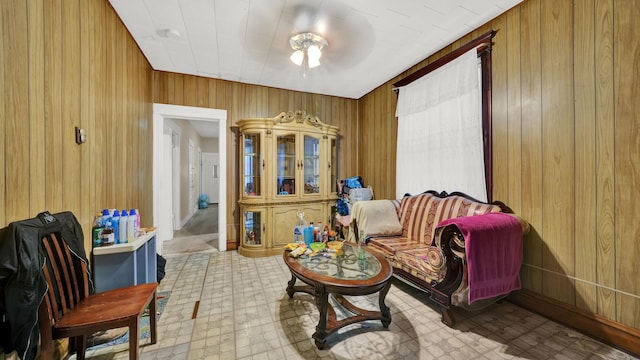 sitting room featuring ceiling fan and wood walls