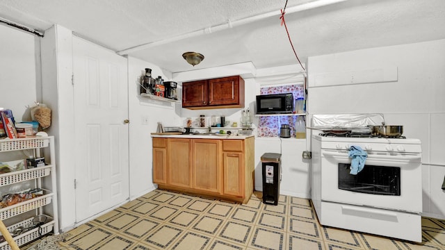 kitchen with black microwave, a textured ceiling, and white range with gas cooktop