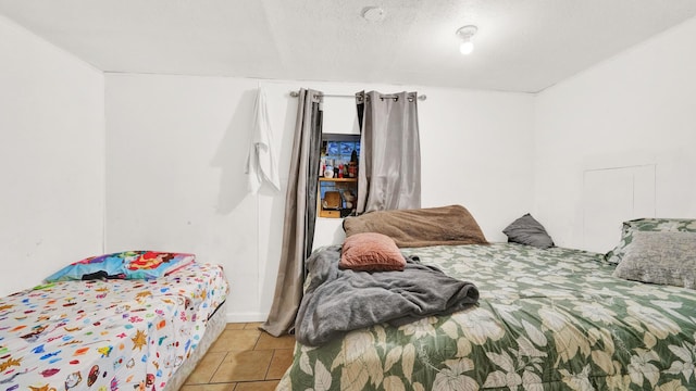 bedroom with a textured ceiling and light tile patterned floors