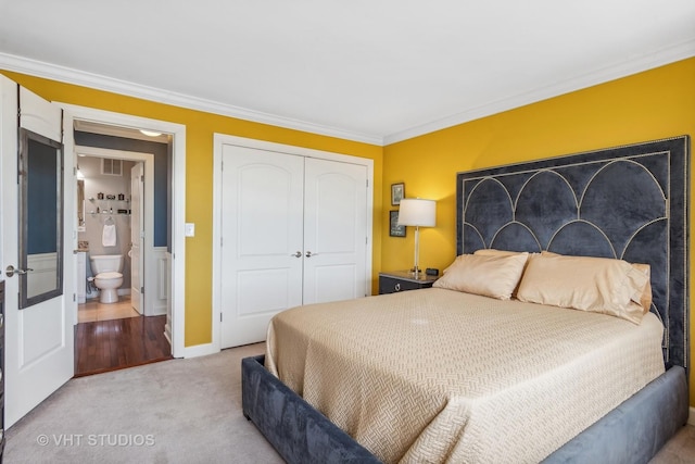 bedroom featuring carpet, ensuite bath, a closet, and crown molding