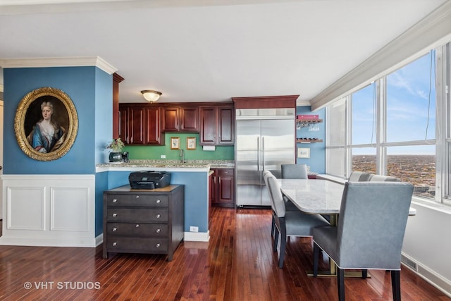 kitchen featuring built in refrigerator, light stone counters, dark hardwood / wood-style flooring, and ornamental molding