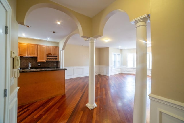 kitchen with ornate columns, light brown cabinets, tasteful backsplash, dark hardwood / wood-style flooring, and sink