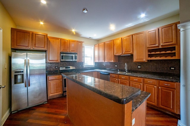 kitchen with a kitchen island, dark wood-type flooring, stainless steel appliances, dark stone countertops, and sink