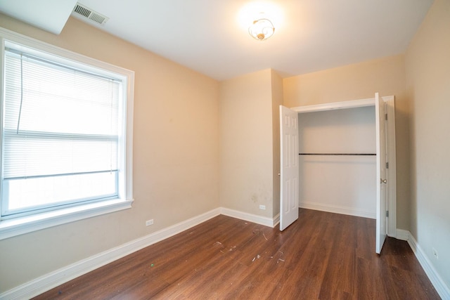 unfurnished bedroom with a closet and dark hardwood / wood-style floors