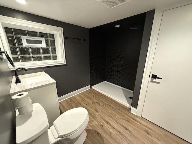 bathroom featuring toilet, a shower, hardwood / wood-style floors, and vanity