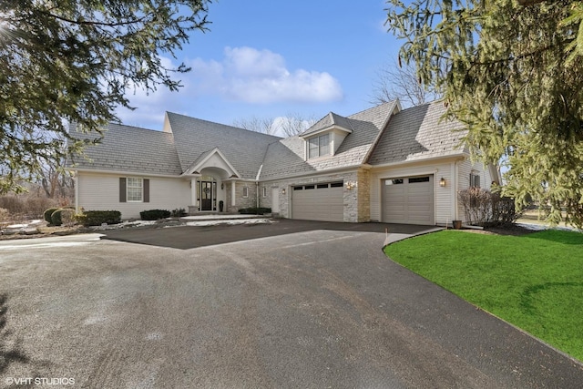 cape cod house featuring a garage and a front lawn