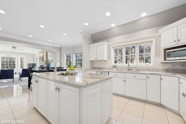 kitchen with a kitchen island, tasteful backsplash, white cabinetry, light tile patterned floors, and light stone countertops