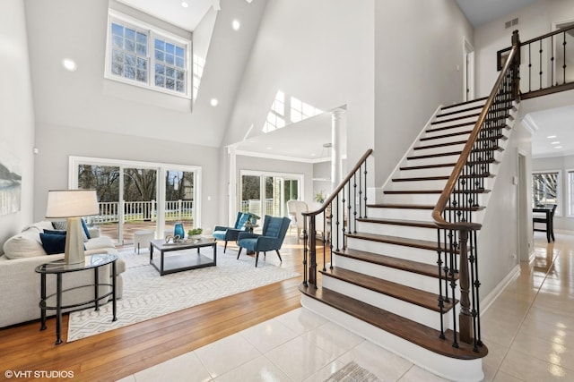 living room featuring light tile patterned floors, ornate columns, and a high ceiling