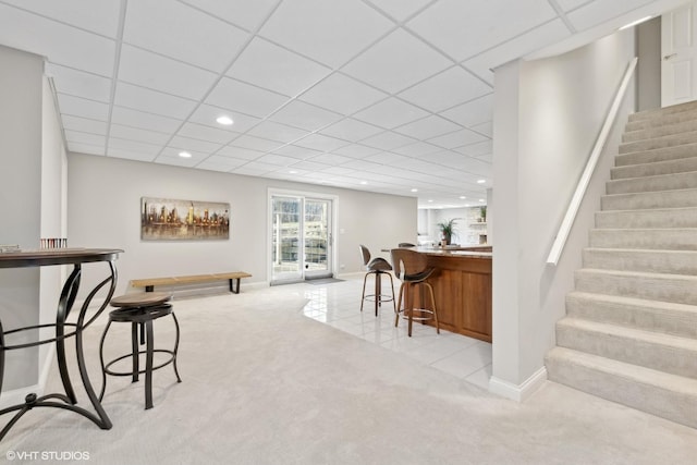 bar featuring a paneled ceiling and light carpet