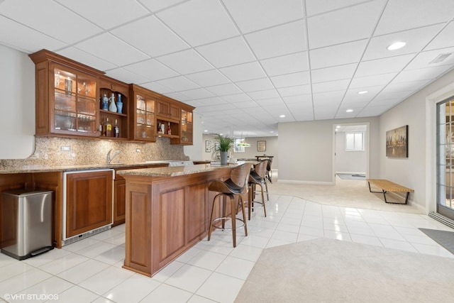 bar with sink, light tile patterned floors, backsplash, and light stone counters