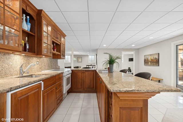 kitchen featuring a breakfast bar, sink, light stone counters, and kitchen peninsula