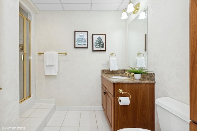 bathroom with tile patterned floors, toilet, a shower with shower door, a paneled ceiling, and vanity