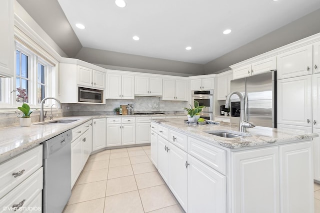 kitchen with appliances with stainless steel finishes, a kitchen island with sink, sink, and white cabinets