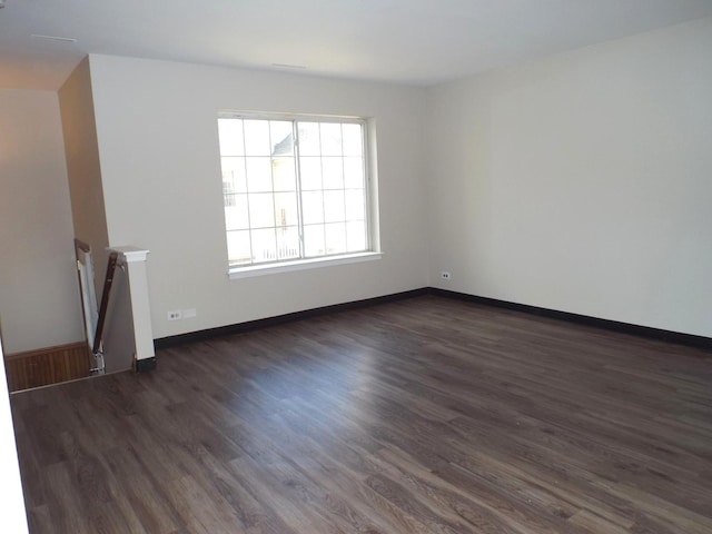 spare room with baseboards and dark wood-style flooring