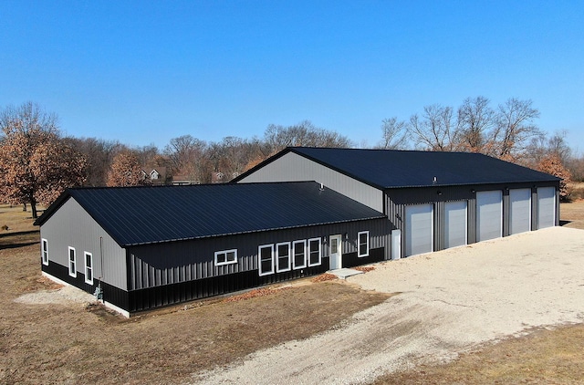 view of front of house with driveway, a detached garage, and metal roof