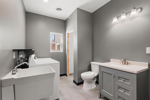 bathroom featuring toilet, vanity, washer and dryer, and hardwood / wood-style floors