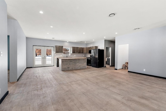 kitchen featuring french doors, a center island, light hardwood / wood-style floors, and black fridge