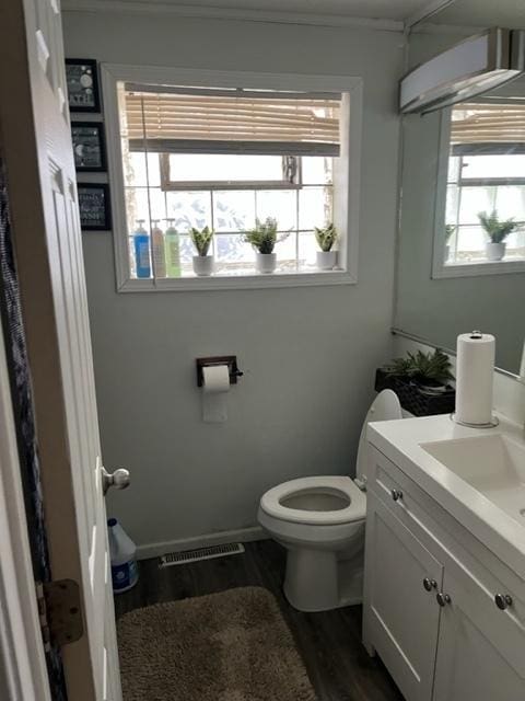 bathroom featuring vanity, hardwood / wood-style flooring, an AC wall unit, and toilet