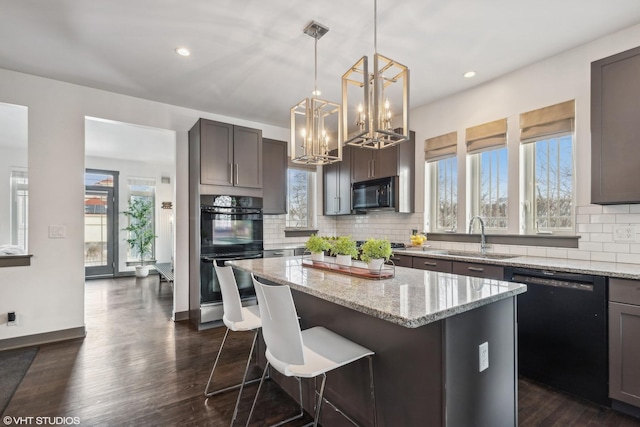 kitchen featuring light stone counters, sink, a kitchen island, and black appliances