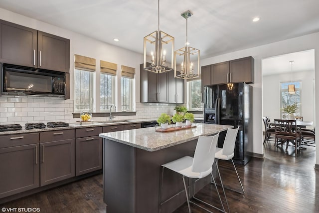 kitchen with sink, decorative light fixtures, black appliances, and a kitchen island