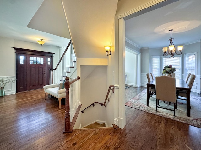 entrance foyer with dark hardwood / wood-style flooring, ornamental molding, and a chandelier