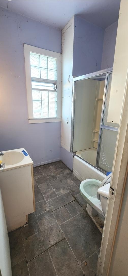 full bathroom featuring toilet, bath / shower combo with glass door, and vanity