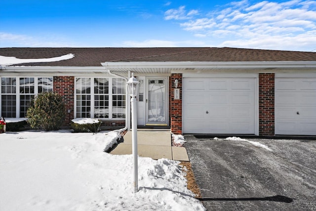 view of front of house featuring an attached garage, brick siding, and a shingled roof