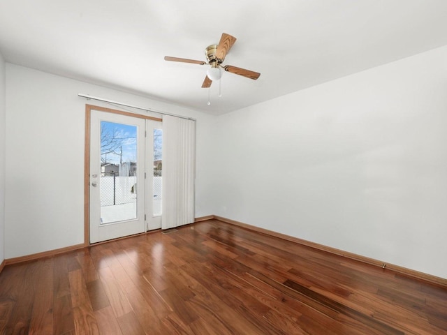 spare room with wood finished floors, a ceiling fan, and baseboards