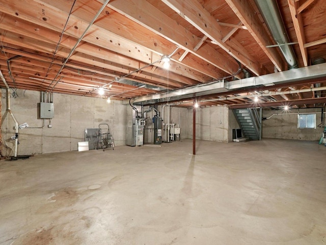 unfinished basement with stairs, electric panel, and gas water heater