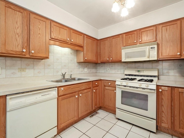 kitchen with white appliances, a sink, light countertops, backsplash, and brown cabinetry