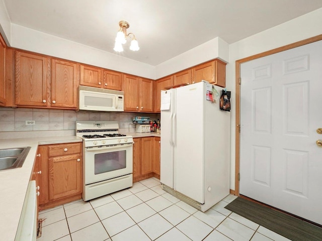 kitchen featuring white appliances, tasteful backsplash, brown cabinetry, an inviting chandelier, and light countertops