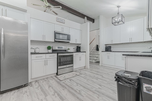 kitchen with appliances with stainless steel finishes, tasteful backsplash, white cabinets, pendant lighting, and light hardwood / wood-style flooring