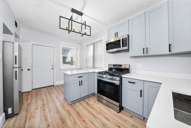 kitchen with decorative light fixtures, light hardwood / wood-style floors, an inviting chandelier, appliances with stainless steel finishes, and gray cabinetry