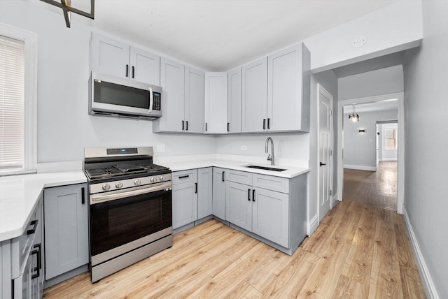 kitchen with sink, gray cabinets, stainless steel appliances, and light wood-type flooring