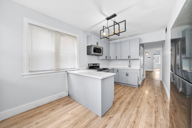 kitchen with light hardwood / wood-style floors, gray cabinets, stainless steel appliances, pendant lighting, and sink