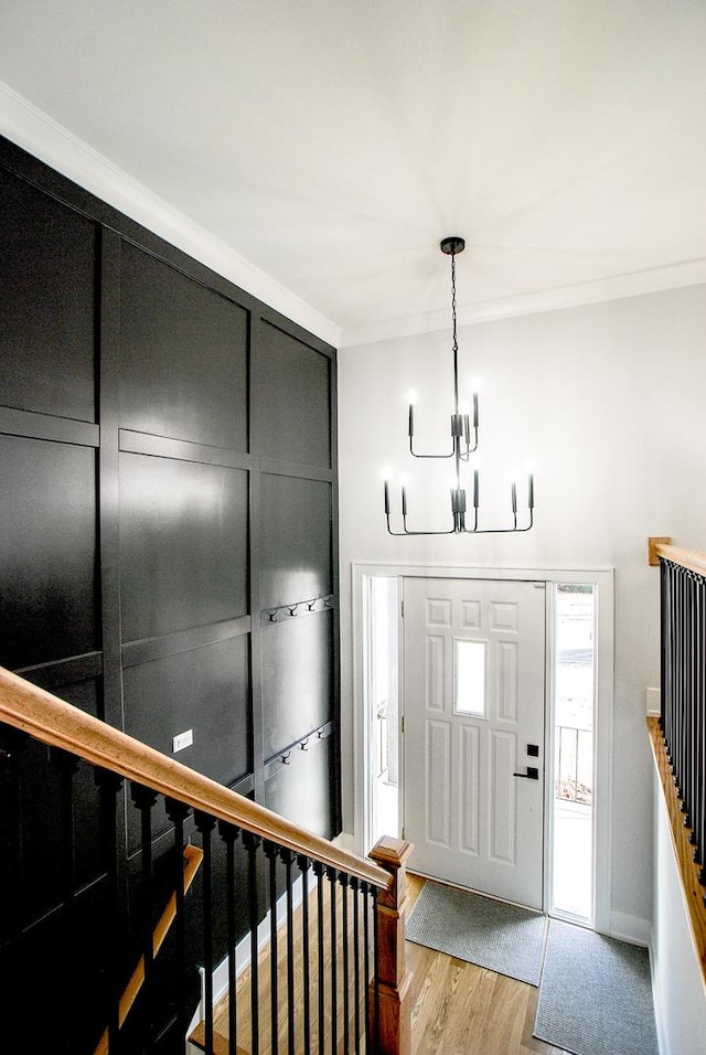 entrance foyer featuring an inviting chandelier, ornamental molding, and light hardwood / wood-style floors