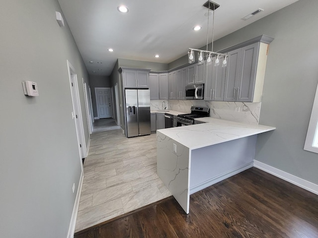 kitchen featuring pendant lighting, gray cabinets, visible vents, appliances with stainless steel finishes, and a peninsula