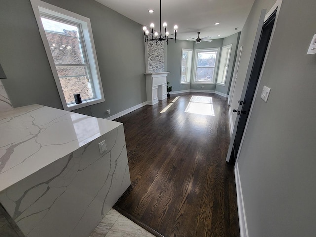 interior space featuring baseboards, ceiling fan, wood finished floors, a fireplace, and recessed lighting