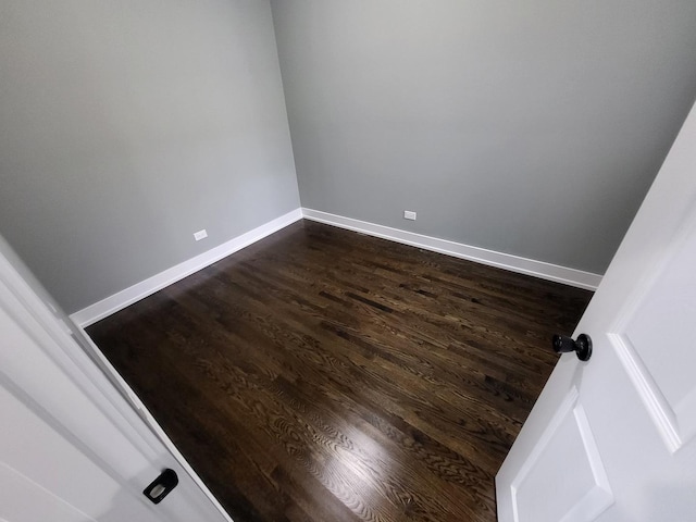 unfurnished room featuring baseboards and dark wood finished floors