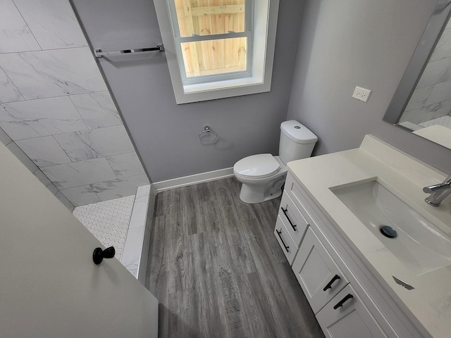 full bath with toilet, wood finished floors, vanity, baseboards, and a shower stall