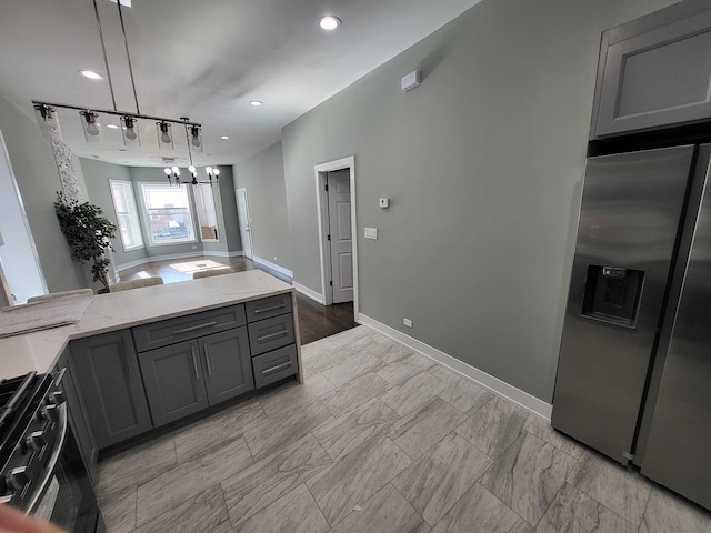 kitchen featuring range with gas stovetop, light stone counters, pendant lighting, stainless steel refrigerator with ice dispenser, and gray cabinets