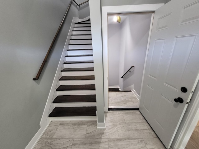 stairway featuring marble finish floor and baseboards