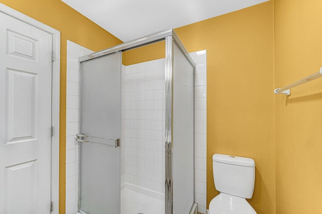 bathroom featuring a shower with shower door and toilet