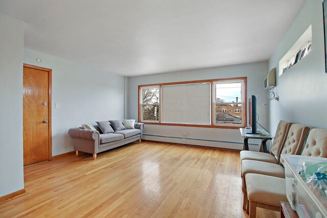 living room with a wall mounted AC, light hardwood / wood-style floors, and a baseboard heating unit