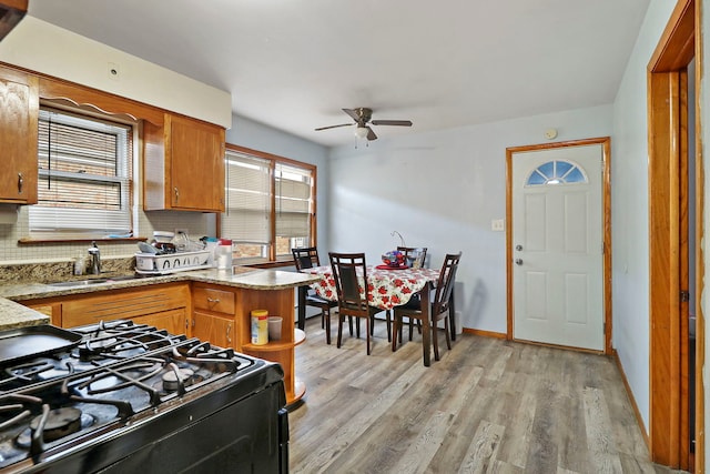 kitchen featuring plenty of natural light, sink, black gas range, and light wood-type flooring