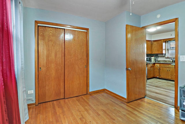 unfurnished bedroom featuring sink, a closet, and light wood-type flooring