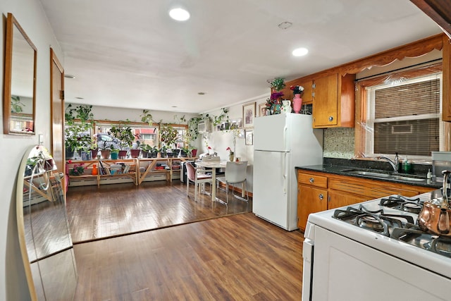 kitchen with sink, backsplash, dark hardwood / wood-style flooring, baseboard heating, and white appliances